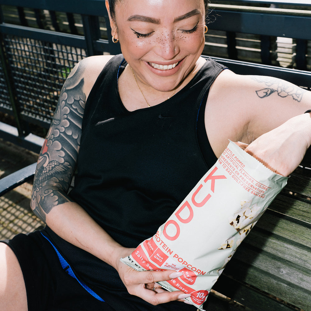 Woman eating KUDO salty sweet kettle korn on a bench
